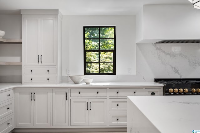 kitchen with light stone countertops, black gas stove, tasteful backsplash, and white cabinetry