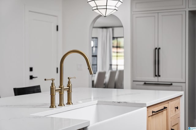 interior details with light stone countertops, light brown cabinets, high end refrigerator, and sink