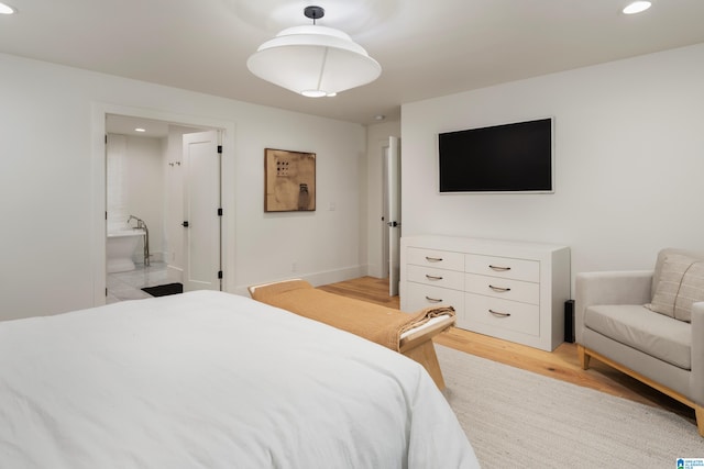 bedroom with light wood-type flooring and ensuite bath