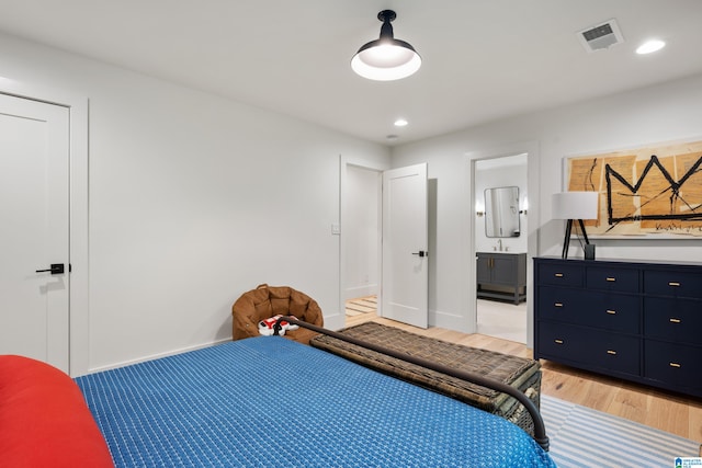 bedroom with connected bathroom and light hardwood / wood-style floors