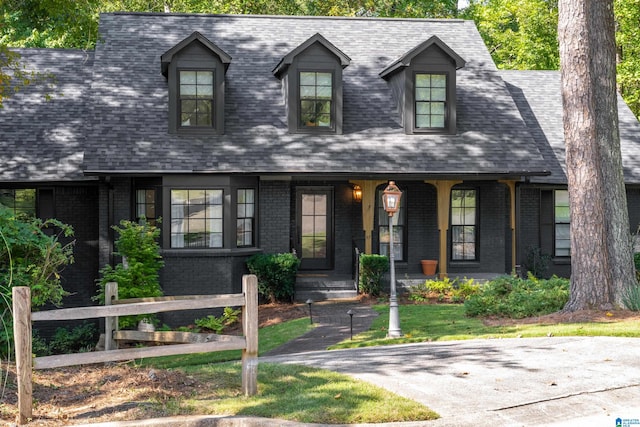 cape cod home featuring covered porch