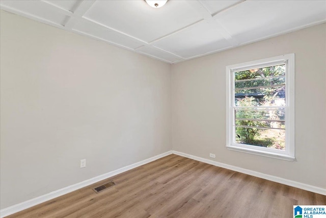 spare room featuring light wood-type flooring and coffered ceiling