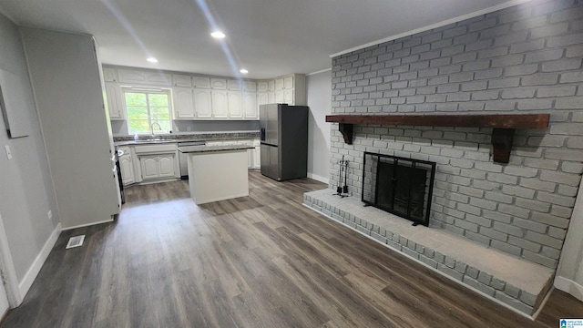 kitchen featuring appliances with stainless steel finishes, white cabinetry, a center island, and dark hardwood / wood-style flooring