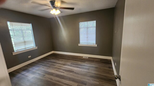 unfurnished room with a wealth of natural light, ceiling fan, a textured ceiling, and dark hardwood / wood-style flooring