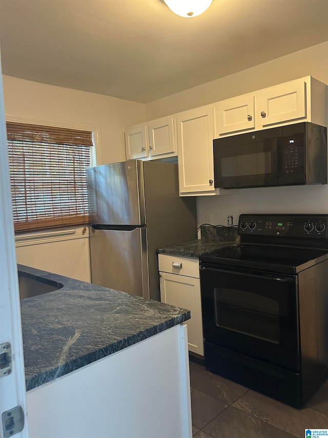 kitchen with black appliances, dark stone countertops, white cabinetry, and dark tile patterned floors