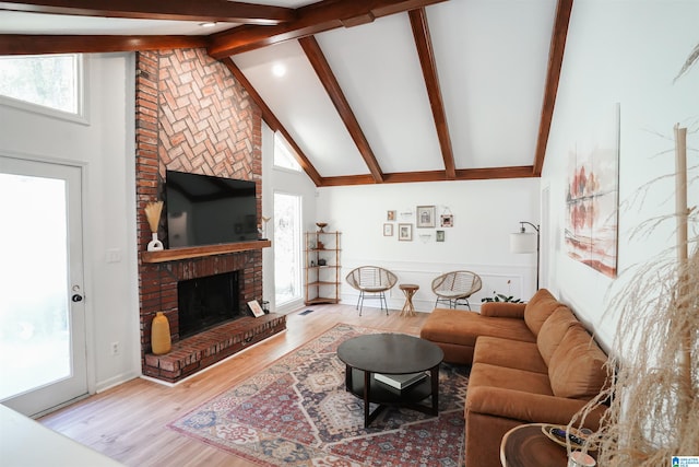 living room with beam ceiling, high vaulted ceiling, a fireplace, and light wood-type flooring