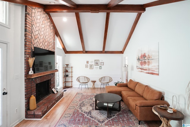 living room featuring light hardwood / wood-style flooring, beam ceiling, high vaulted ceiling, and a fireplace