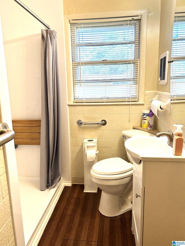 bathroom with tile walls, hardwood / wood-style floors, curtained shower, vanity, and toilet