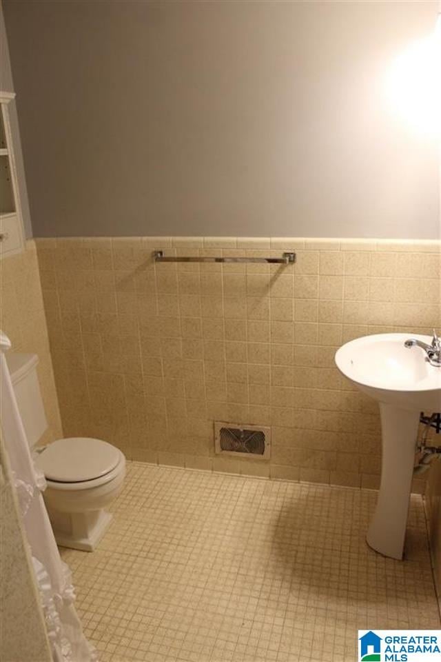 bathroom featuring tile walls, tile patterned floors, and toilet