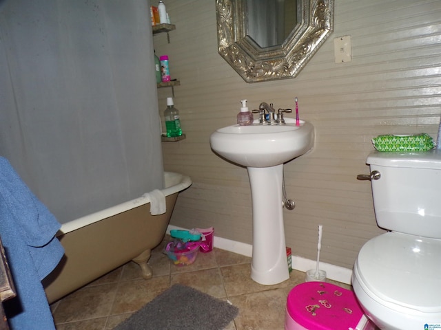 full bath with tile patterned flooring, wooden walls, toilet, baseboards, and a bathtub