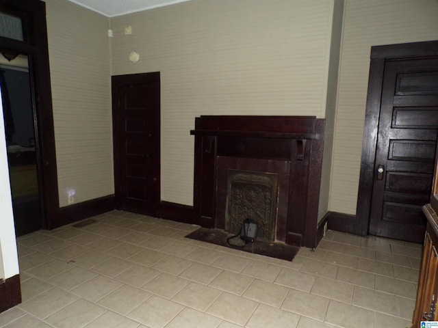 unfurnished living room with a fireplace with flush hearth, baseboards, and light tile patterned flooring