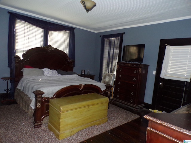 bedroom featuring wood finished floors, crown molding, and baseboards