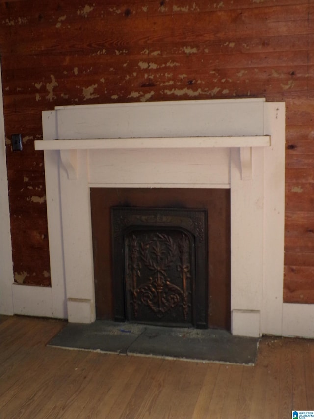 interior details with a fireplace with flush hearth, wood finished floors, and wood walls
