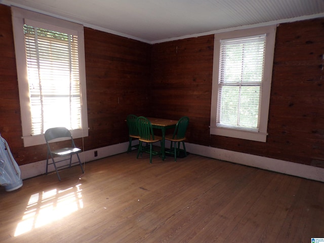 unfurnished room featuring hardwood / wood-style flooring, wood walls, and ornamental molding