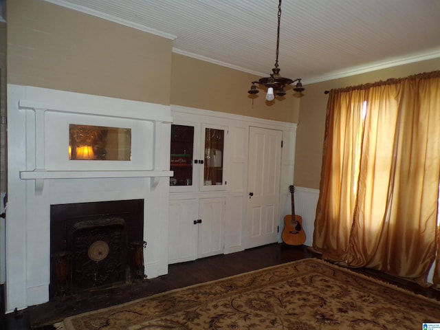 interior space featuring crown molding, an inviting chandelier, a wainscoted wall, a fireplace, and dark wood finished floors