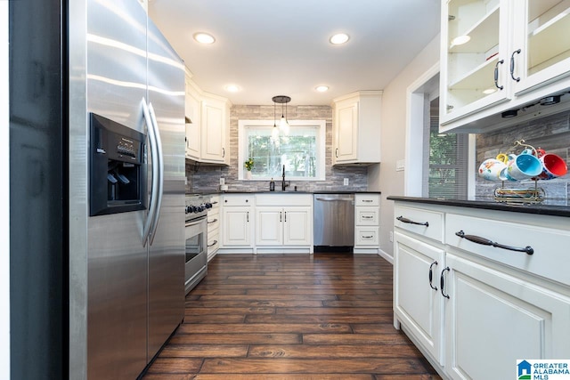 kitchen featuring hanging light fixtures, dark wood-type flooring, white cabinetry, appliances with stainless steel finishes, and decorative backsplash