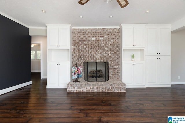 unfurnished living room featuring a brick fireplace, dark hardwood / wood-style flooring, ornamental molding, ceiling fan, and built in features