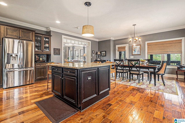 kitchen featuring stainless steel refrigerator with ice dispenser, light hardwood / wood-style floors, a center island, and light stone counters