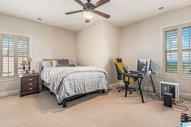 bedroom with ceiling fan, light carpet, and multiple windows