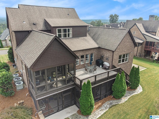 rear view of property with a sunroom, a yard, and central air condition unit