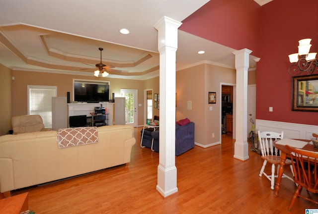 living room with crown molding, ornate columns, light wood-type flooring, and ceiling fan