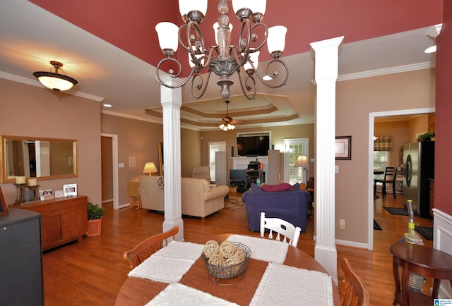 dining space featuring ornate columns, hardwood / wood-style flooring, crown molding, and ceiling fan with notable chandelier