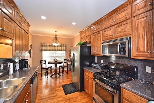 kitchen featuring stainless steel appliances, sink, crown molding, light hardwood / wood-style floors, and tasteful backsplash