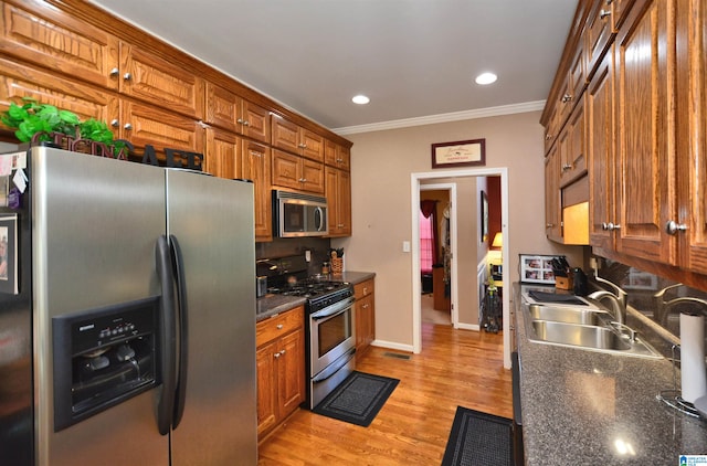 kitchen featuring crown molding, stainless steel appliances, sink, and light wood-type flooring