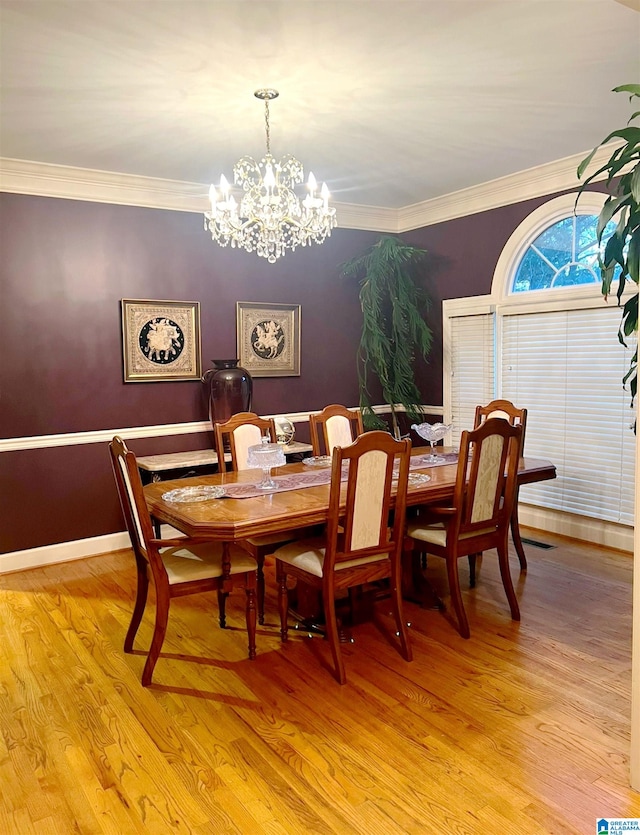 dining area with ornamental molding, a notable chandelier, and light wood-type flooring