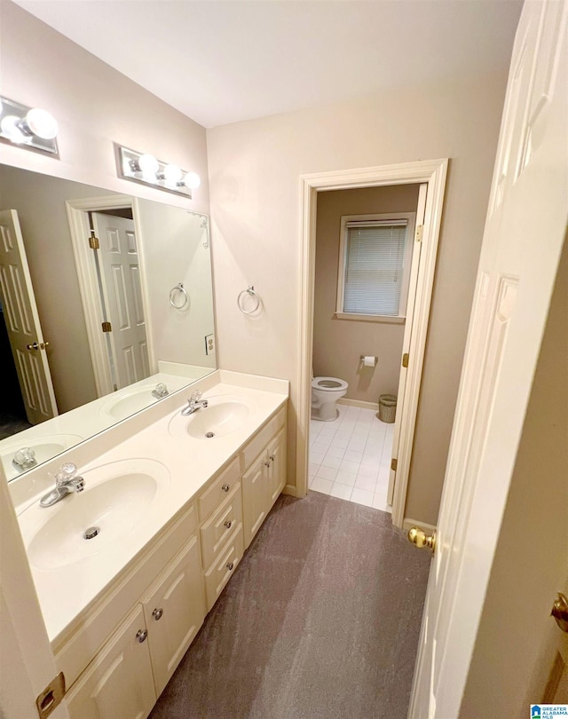 bathroom with toilet, vanity, and tile patterned floors