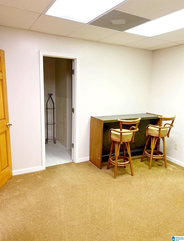 carpeted home office with a drop ceiling and indoor bar