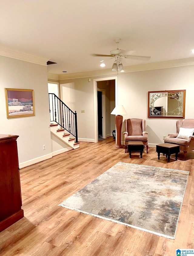 living area featuring light hardwood / wood-style flooring, ceiling fan, and crown molding