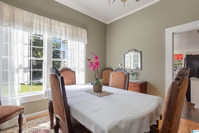 dining room with light wood-type flooring and crown molding