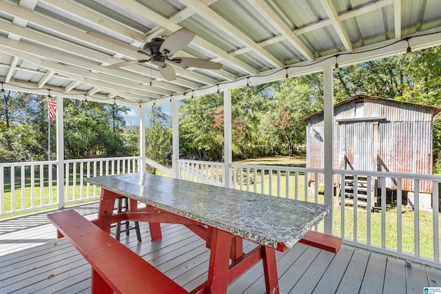 wooden terrace with ceiling fan, a yard, and a storage unit