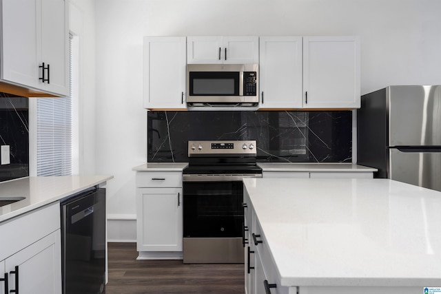 kitchen with dark wood-type flooring, backsplash, white cabinets, and appliances with stainless steel finishes