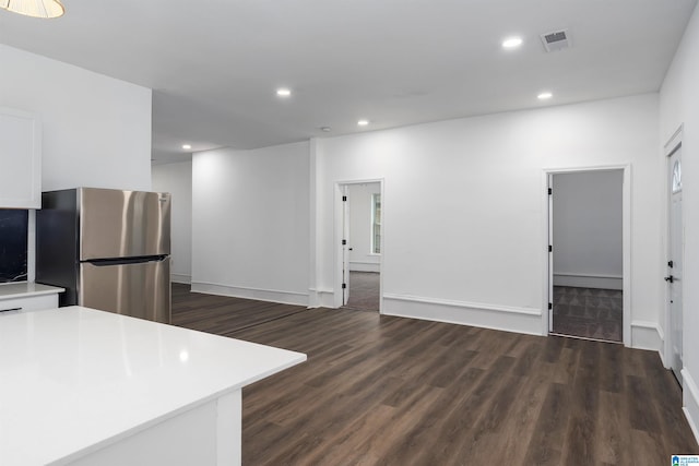 kitchen featuring stainless steel fridge, dark wood-type flooring, and white cabinetry