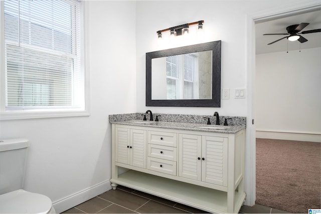 bathroom with ceiling fan, a wealth of natural light, toilet, and vanity