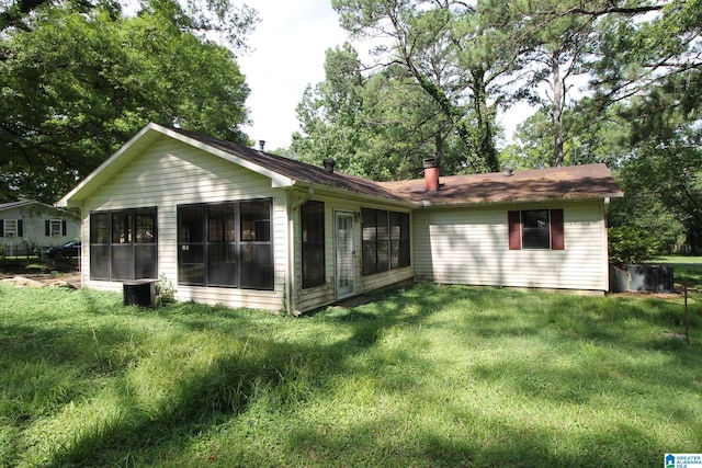 rear view of house featuring a sunroom and a lawn