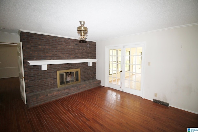 unfurnished living room with a brick fireplace, dark wood-type flooring, french doors, ornamental molding, and a textured ceiling