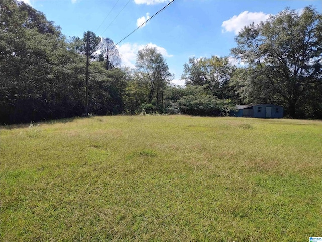 view of green lawn featuring a view of trees