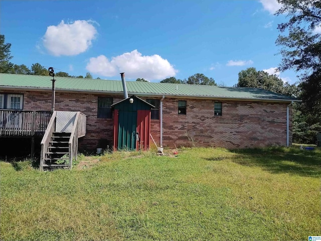 back of house with a deck, a lawn, stairway, brick siding, and metal roof