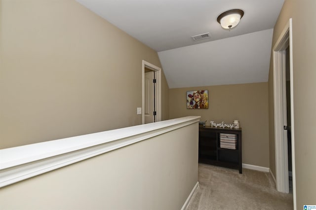 hallway with vaulted ceiling and light colored carpet