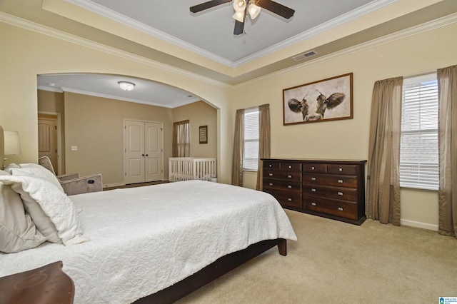 bedroom featuring light carpet, a closet, ceiling fan, and crown molding