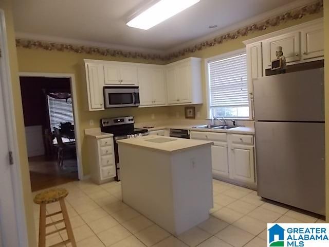 kitchen with stainless steel appliances, white cabinets, a kitchen island, and sink