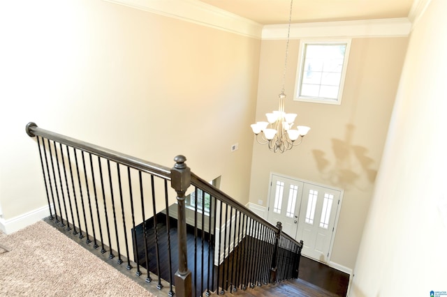 staircase with ornamental molding, hardwood / wood-style flooring, and a chandelier