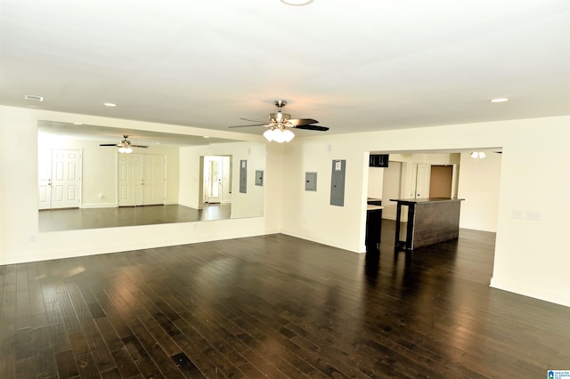 unfurnished living room featuring electric panel, ceiling fan, and dark hardwood / wood-style flooring