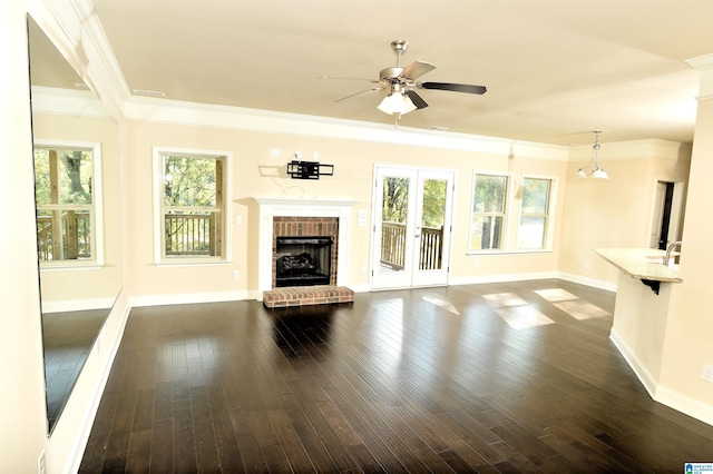 unfurnished living room featuring a brick fireplace, dark hardwood / wood-style flooring, ornamental molding, and ceiling fan