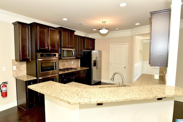 kitchen featuring kitchen peninsula, appliances with stainless steel finishes, light stone countertops, and hanging light fixtures