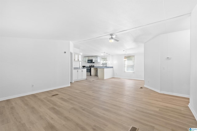 unfurnished living room featuring vaulted ceiling, light hardwood / wood-style floors, and ceiling fan