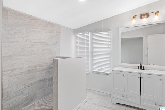 bathroom with a tile shower, lofted ceiling, and vanity